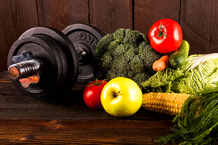 Importanza della dieta, manubri ortaggi e frutta disposti su un tavolo ne esprimono il concetto